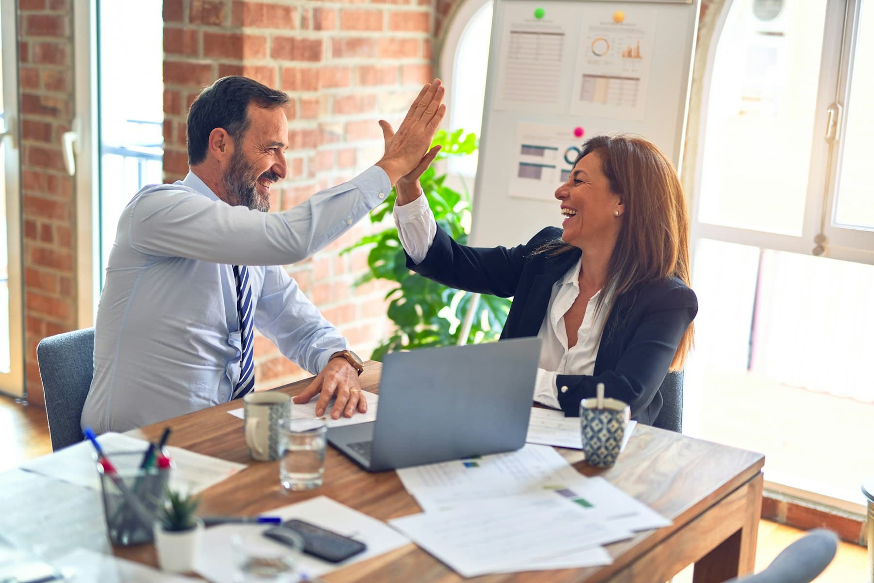 Two professionals celebrating an agreement during a business meeting